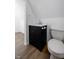 Attic bathroom with a black vanity, toilet, white walls, and wood floors at 3822 Haverhill Dr, Anderson, IN 46013