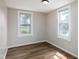 Bright bedroom with two windows, neutral paint, wood-look flooring, and white trim at 3822 Haverhill Dr, Anderson, IN 46013