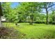 Lush backyard featuring mature trees, green lawn, lounge chair, and bench, perfect for outdoor enjoyment at 4340 Ashbourne Ln, Indianapolis, IN 46226