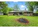 View of the brick home exterior, fire pit, and lush, overgrown green grass in the backyard at 4340 Ashbourne Ln, Indianapolis, IN 46226