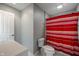 Full bathroom with red striped shower curtain, toilet, and white door at 4446 Lakeridge Dr, Indianapolis, IN 46234