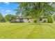 View of the home's stone exterior with a deck and well-manicured lawn at 5550 W Mooresville Rd Byp, Indianapolis, IN 46221
