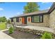 Charming stone home featuring a decorative wood door, landscaped yard, and beautiful exterior lighting at 5550 W Mooresville Rd Byp, Indianapolis, IN 46221