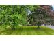 Verdant front yard showcasing the home with its stone exterior, and decorative front door framed by mature trees at 5550 W Mooresville Rd Byp, Indianapolis, IN 46221