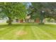 Well-manicured front yard showcasing the stone facade of the home and mature trees at 5550 W Mooresville Rd Byp, Indianapolis, IN 46221