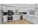 Modern kitchen with stainless steel appliances, white cabinets, black backsplash and light wood flooring at 5550 W Mooresville Rd Byp, Indianapolis, IN 46221