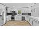 Modern kitchen with stainless steel appliances, white cabinets, black backsplash and light wood flooring at 5550 W Mooresville Rd Byp, Indianapolis, IN 46221
