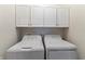 A bright laundry room featuring a washer, dryer, and white storage cabinets above at 564 Parkhurst Ct, Greenwood, IN 46142
