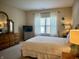 Well-lit bedroom with a bed, curtains, and a wooden dresser at 5932 Edelle Dr, Indianapolis, IN 46237