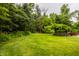Lush backyard featuring expansive green lawn and mature trees offering privacy at 6295 N Olney St, Indianapolis, IN 46220