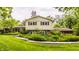 Two-story home with a brick foundation, a light yellow siding, and surrounded by lush greenery at 6295 N Olney St, Indianapolis, IN 46220
