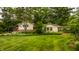 Exterior view of a well-kept home with a lush green lawn and mature trees, providing privacy at 6295 N Olney St, Indianapolis, IN 46220
