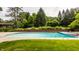 Backyard pool with lush green surroundings and brick retaining wall creating a private oasis at 6295 N Olney St, Indianapolis, IN 46220