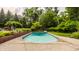 Backyard swimming pool with surrounding concrete patio and partial brick fence enclosed by mature trees at 6295 N Olney St, Indianapolis, IN 46220