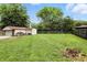 Large backyard with green grass, surrounded by mature trees and a wooden fence at 7113 Chandler Dr, Indianapolis, IN 46217