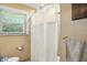 Clean bathroom with a white shower curtain and a window providing natural light and backyard views at 7113 Chandler Dr, Indianapolis, IN 46217