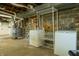 A functional basement laundry area with machines, metal racks, a furnace, and exposed brick walls at 7727 Huff St, Indianapolis, IN 46259