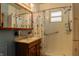 Well-lit bathroom with a shower, seashell-themed shower curtain, sink with a wooden cabinet, and a large mirror at 7727 Huff St, Indianapolis, IN 46259