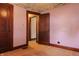 A bedroom with wood trim, salmon walls and carpet and an open door to a second room at 7727 Huff St, Indianapolis, IN 46259