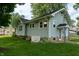 A well-maintained home exterior includes green grass, lush plants, and a backup generator for energy needs at 7727 Huff St, Indianapolis, IN 46259