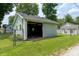 A detached garage with open doors is enclosed by a chain-link fence and grassy yard at 7727 Huff St, Indianapolis, IN 46259