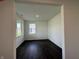 A bright, open living space showcasing dark hardwood floors and white walls with large windows for ample natural light at 7909 Magnolia St, New Palestine, IN 46163