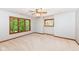 Spacious bedroom with ceiling fan, neutral carpet and multiple windows looking onto mature trees at 8004 Lafayette Rd, Indianapolis, IN 46278