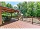 Wooden deck with a gazebo and an outdoor dining set, surrounded by trees and a playset at 8004 Lafayette Rd, Indianapolis, IN 46278