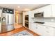Close up of updated kitchen with stainless steel appliances, white cabinets, and hardwood flooring at 8004 Lafayette Rd, Indianapolis, IN 46278