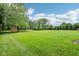 Expansive backyard with lush green grass, mature trees, and a charming red barn in the distance at 8301 Cooper Ln, Zionsville, IN 46077