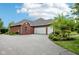 Spacious three-car garage and brick exterior with manicured landscaping and blue sky backdrop at 8301 Cooper Ln, Zionsville, IN 46077