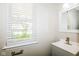 This powder room features a gray vanity with white sink and natural light from the window at 8310 Becks Mill Ln, Indianapolis, IN 46113