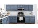 A cozy kitchen features blue cabinets, white countertops, and stainless steel appliances at 8753 Champions Dr, Indianapolis, IN 46256