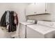 Well-lit laundry room features a washer and dryer, white cabinets and walls, and coat racks for extra storage at 8753 Champions Dr, Indianapolis, IN 46256