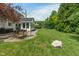 Spacious backyard features a stone patio with a fire pit, sunroom addition, and mature trees at 8904 Carnation Dr, Noblesville, IN 46060