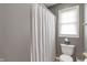 Neutral bathroom featuring a shower with a white curtain and a toilet next to a window at 8904 Carnation Dr, Noblesville, IN 46060