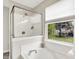 Bright bathroom features a luxurious tub with tile backsplash and a glass-enclosed shower with built-in shelves at 9653 Cypress Way, Carmel, IN 46032