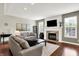 Cozy living room with fireplace, hardwood floors, and bright light from the windows at 9653 Cypress Way, Carmel, IN 46032