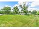 Spacious backyard with lush green grass, mature trees, and a partial view of the home and outbuildings at 1130 E 105Th St, Carmel, IN 46280