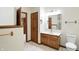 Well-lit bathroom with wood cabinets, a white countertop sink, and a white toilet at 1326 Pebble Brook Dr, Noblesville, IN 46062