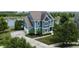 Aerial view of blue home with an attached garage, lake view, mature trees, and a well-manicured lawn at 13895 Cloverfield Cir, Fishers, IN 46038