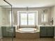 Bright bathroom featuring a tub, windows with shutters, double sinks, modern light fixtures, and decorative mirrors at 13895 Cloverfield Cir, Fishers, IN 46038