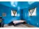 A blue carpeted bedroom with two windows, a single bed, and minimalist decor at 2610 Caroline Ave, Indianapolis, IN 46218