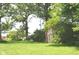 Lush yard featuring a small red shed, bordered by mature trees, adding character and storage to the property at 3115 E 400 S, Anderson, IN 46017