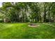 Lush backyard with a fire pit, mature trees, and a playset in the distance at 4191 N Graham Rd, Whiteland, IN 46184