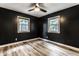 Bedroom with dark walls, light wood-look floors, a ceiling fan, and bright windows at 4191 N Graham Rd, Whiteland, IN 46184