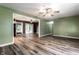 Spacious living room featuring wood-look floors, ceiling fan, and an open doorway leading to the adjacent sunroom at 4191 N Graham Rd, Whiteland, IN 46184