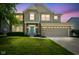 Charming two-story home at dusk featuring a manicured lawn, a two-car garage, and a welcoming turquoise-colored front door at 6471 W Clearview Dr, McCordsville, IN 46055