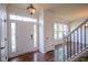 Bright foyer with hardwood floors, a staircase with white railings, and a view into an adjacent room at 6471 W Clearview Dr, McCordsville, IN 46055
