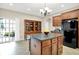 Bright kitchen features a stone countertop island, black appliances, wood cabinets, and a glass sliding door to the backyard at 6691 Beekman Pl, Zionsville, IN 46077
